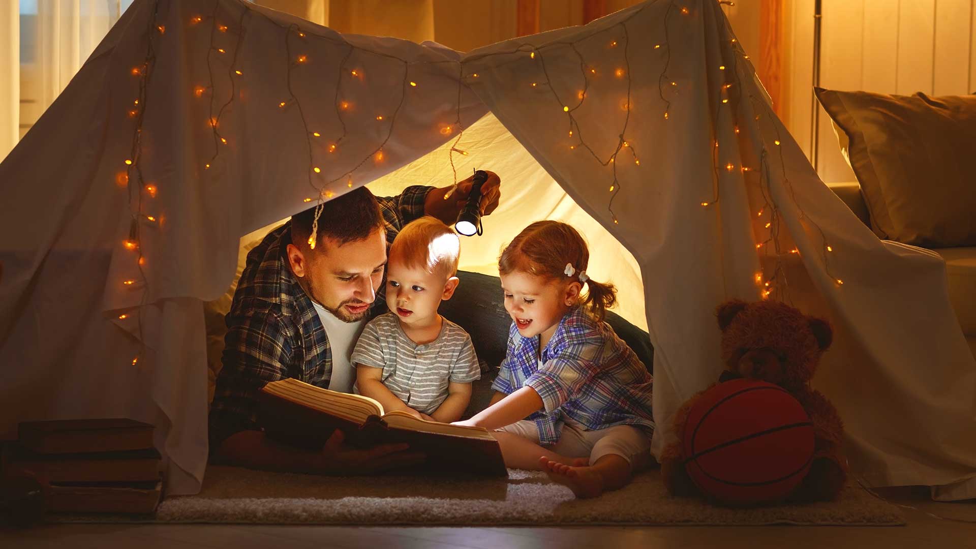 Family reading book in homemade fort